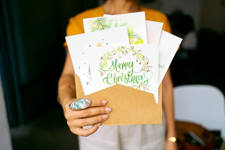 A close-up view of hands holding decorative Christmas cards in an envelope.