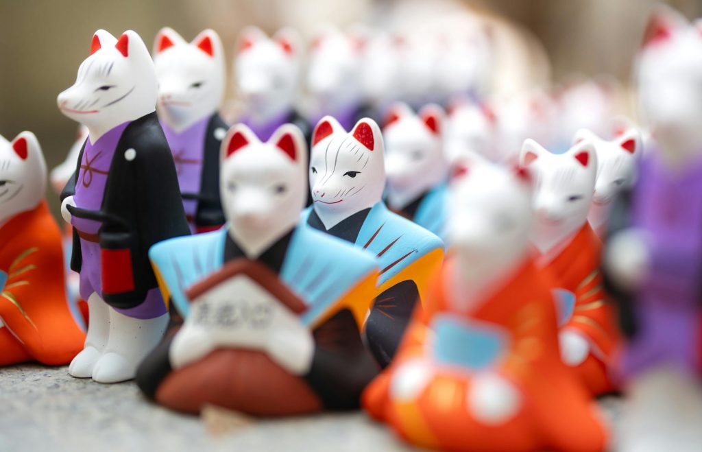 Vibrant kitsune figurines on display in a Kyoto market, symbolizing Japanese folklore and tradition.
