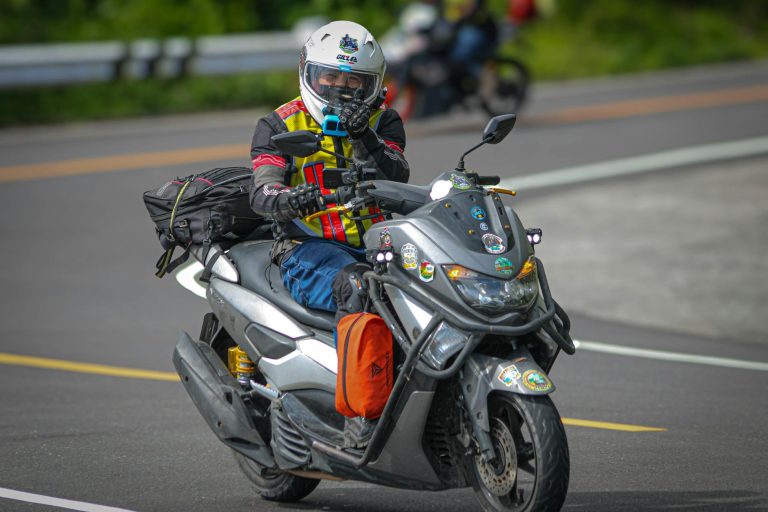A motorcyclist riding with gear on a scenic road in Tabaco City, showcasing adventure and travel.