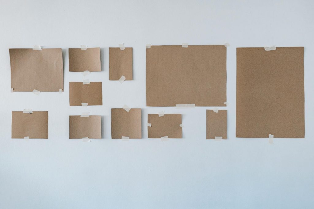 Variety of cardboard sheets taped to white wall for art display or planning.