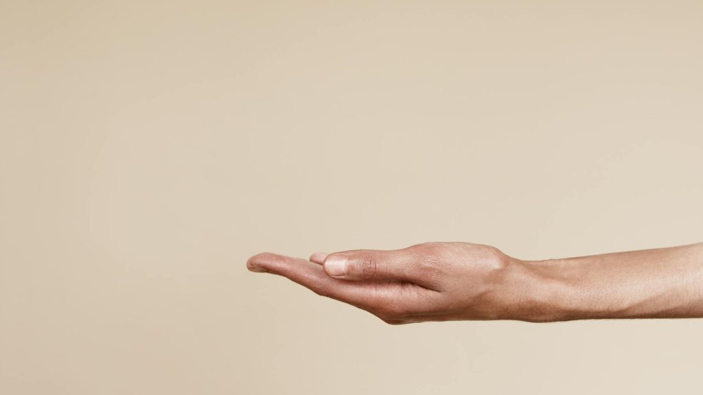 Close-up of an open hand reaching out isolated on a neutral background, symbolizing offering or receiving.