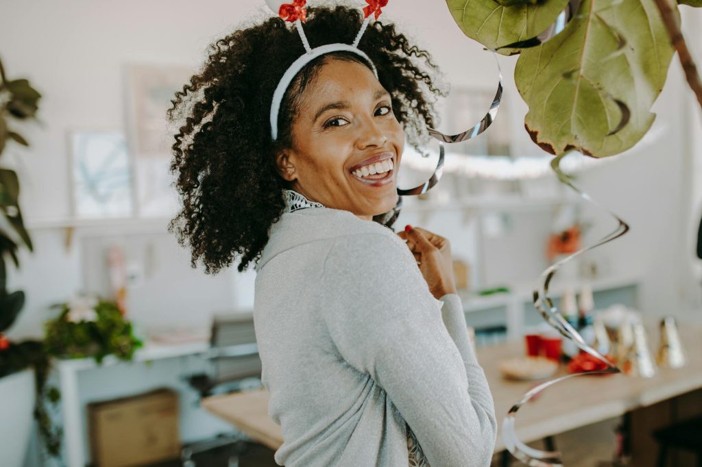 Smiling woman enjoying a festive office holiday party with decorations.