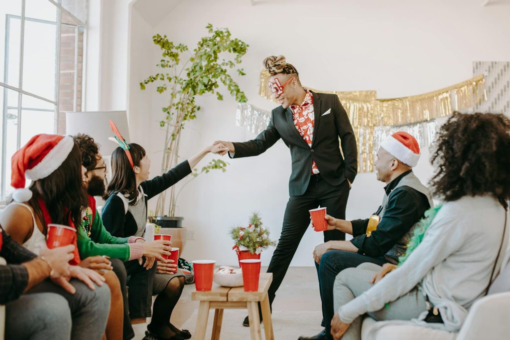 A lively indoor holiday party with friends in festive attire sharing drinks and laughter.
