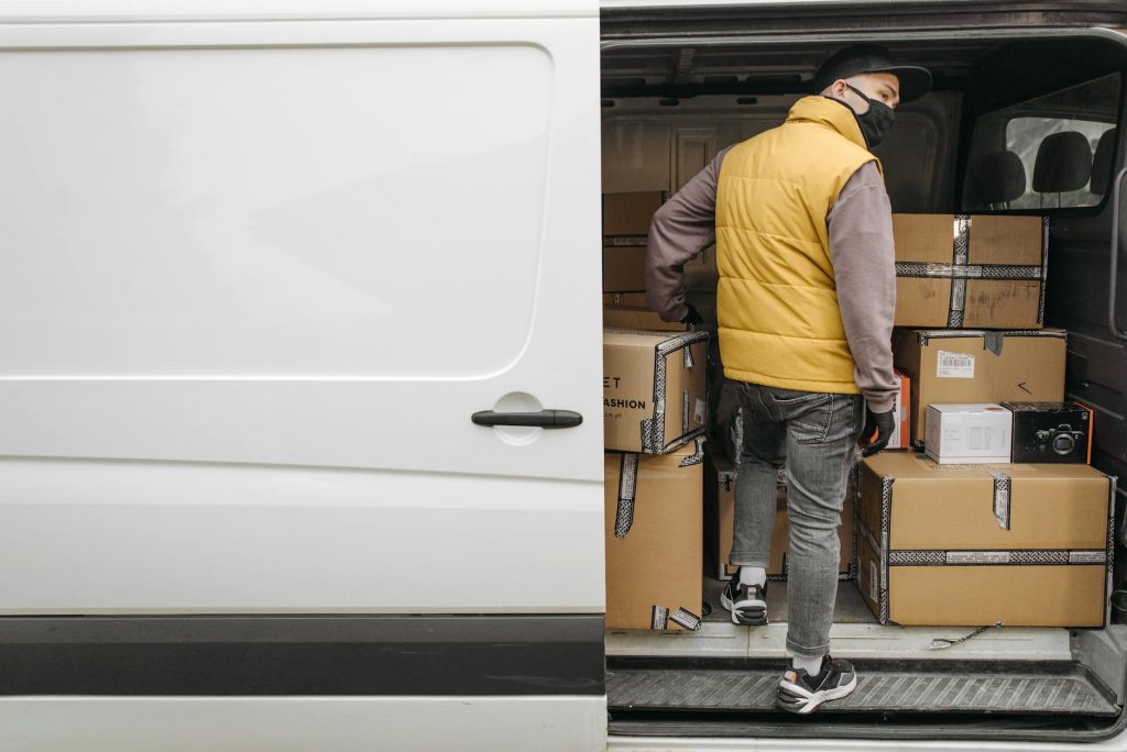 A deliveryman unloading packages from a van, showcasing modern logistics.