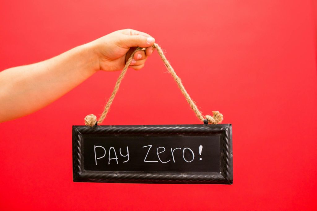 A hand holds a sign displaying 'Pay Zero' on a vibrant red background, emphasizing a free or zero-cost concept.