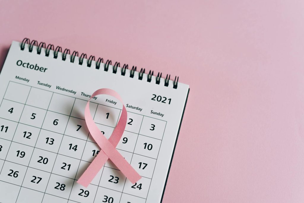 Close-up of a pink ribbon on an October 2021 calendar, symbolizing breast cancer awareness.