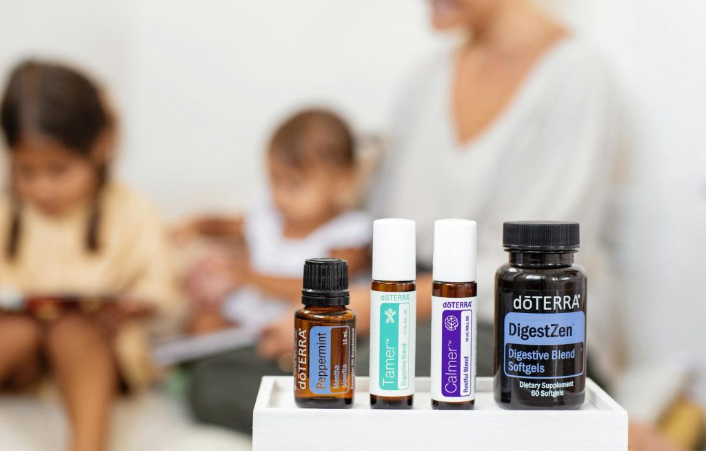 Close-up of doTERRA essential oils and supplements with people in a blurred background.
