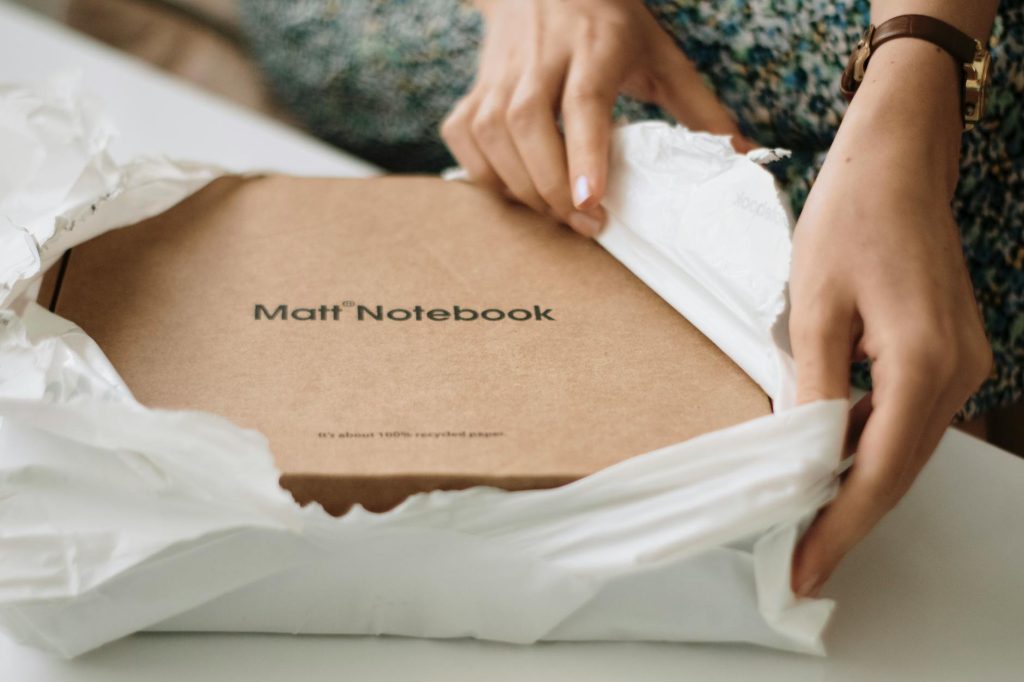 Close-up of hands unboxing a Matt notebook made from recycled paper, emphasizing sustainability.
