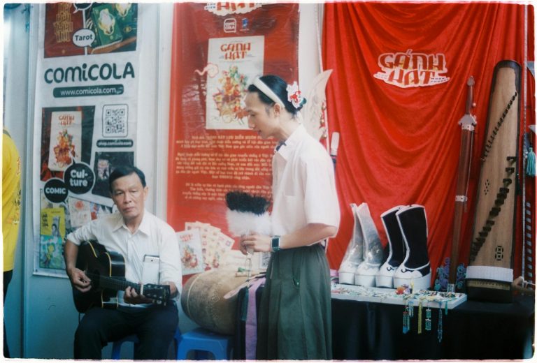 Traditional Vietnamese musical performance with guitar and props at Ho Chi Minh City market.