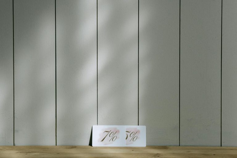 Minimalist discount cards showcasing 7% and 5% set against a wooden backdrop with soft lighting.