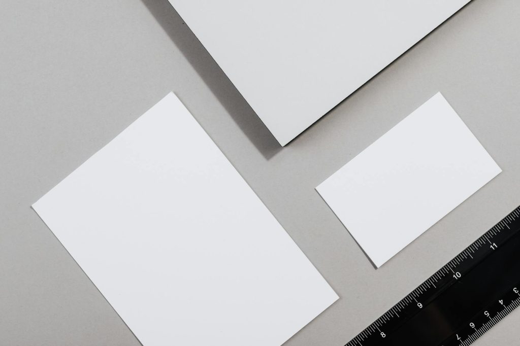Flat lay of blank paper sheets and a ruler on a gray background.