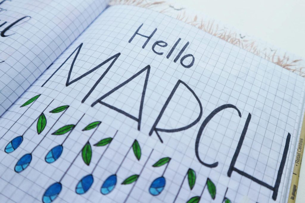 Open notebook with "Hello March" illustration featuring colorful raindrops and leaves.