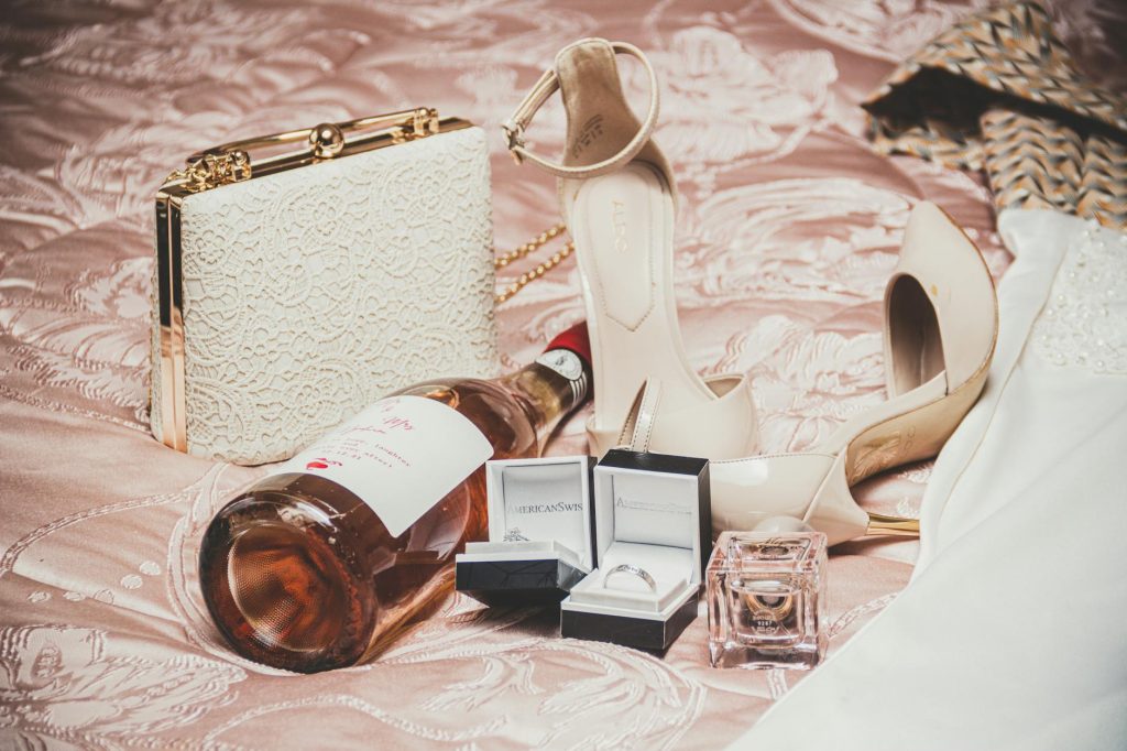 Elegant luxury fashion items and champagne bottle on a bed setting.