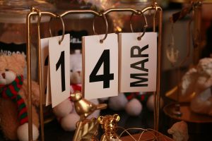 Close-up of a stylish desk calendar showing March 14, surrounded by decorative items.