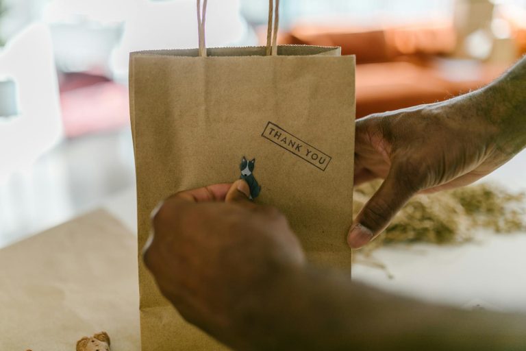 Close-up of hands holding a thank you paper bag, symbolizing gratitude and small business packaging.