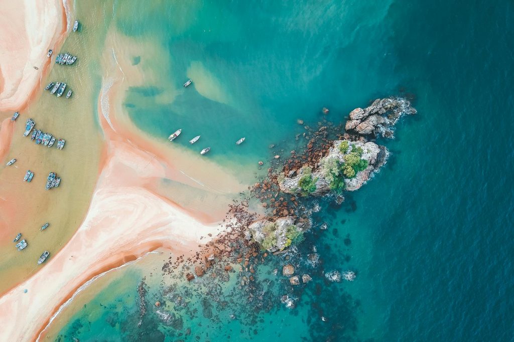 Scenic aerial view of turquoise clear sea water and sandy shoreline with moored boats