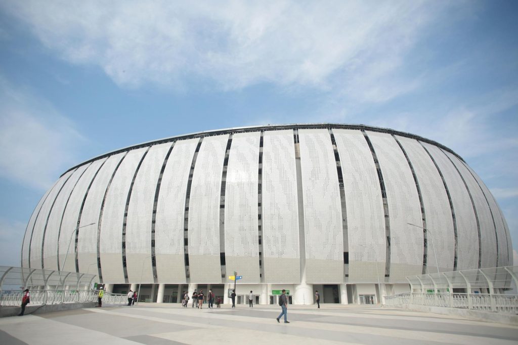 Wide view of the modern Jakarta International Stadium on a sunny day, showcasing its unique architecture.