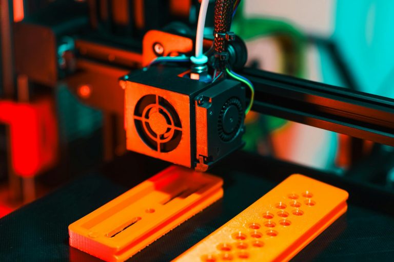 Detailed view of a 3D printer in action, extruding orange plastic components.