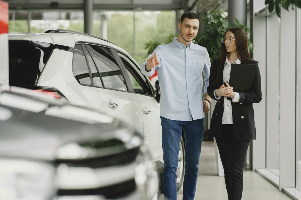 Customer and salesperson discussing a vehicle inside a modern car dealership showroom.