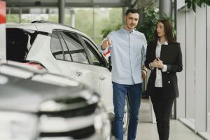 Customer and salesperson discussing a vehicle inside a modern car dealership showroom.
