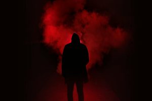 A mysterious silhouette standing against a backdrop of dramatic red smoke.