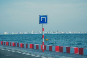 Coastal roadway with a turn sign against a city skyline in Da Nang, Vietnam.