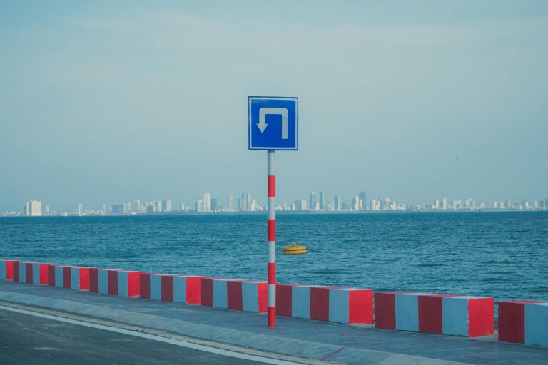 Coastal roadway with a turn sign against a city skyline in Da Nang, Vietnam.