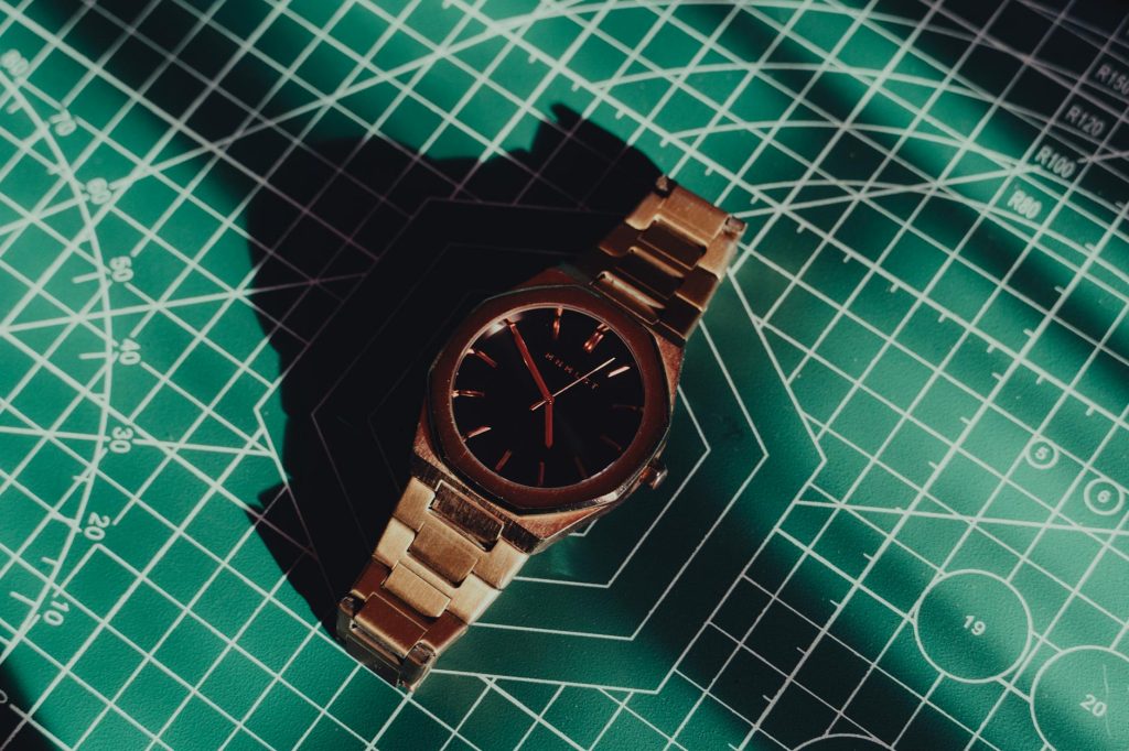 A classic watch displayed on a geometric mat with shadows highlighting its elegance.