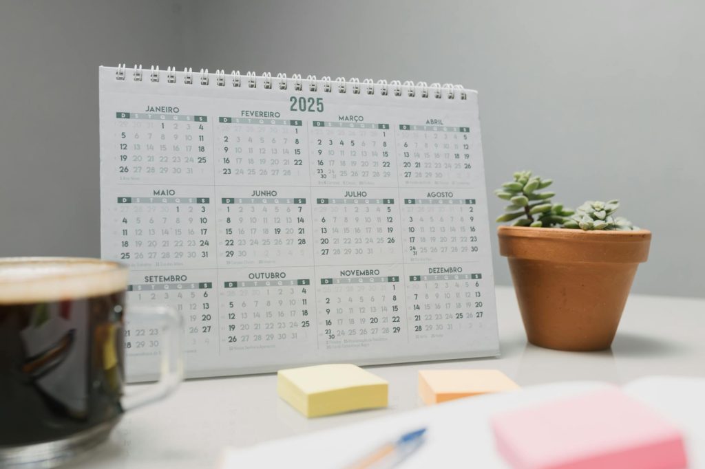 A 2025 desk calendar with coffee, sticky notes, and succulents for planning.