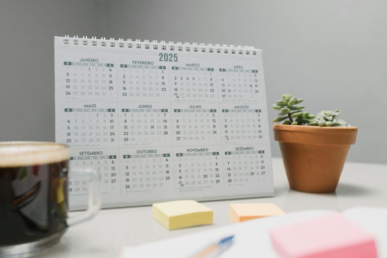 A 2025 desk calendar with coffee, sticky notes, and succulents for planning.