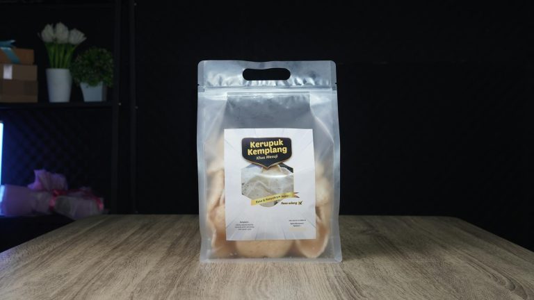 Clear packaging of Kerupuk Kemplang shrimp crackers on a wooden table.
