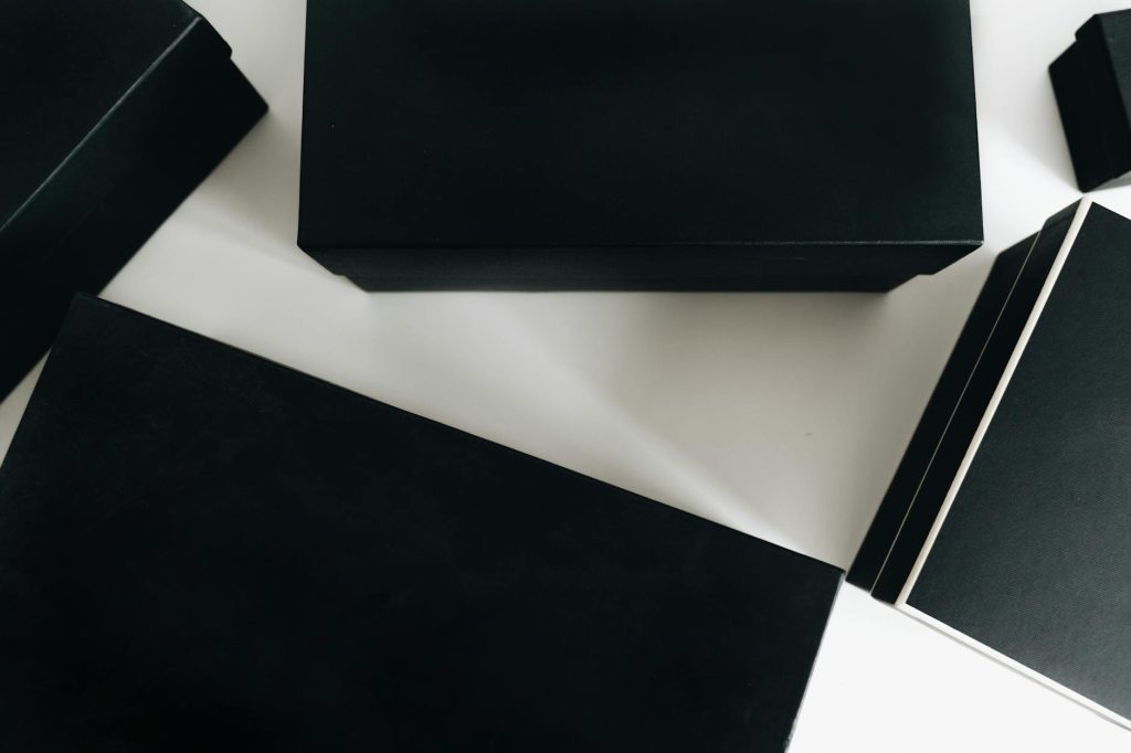 Top view of sleek black boxes arranged artfully on a white surface, showcasing minimalist design.