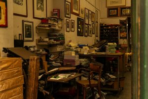 A cluttered vintage print shop interior in Florence, Italy, filled with books and artwork.