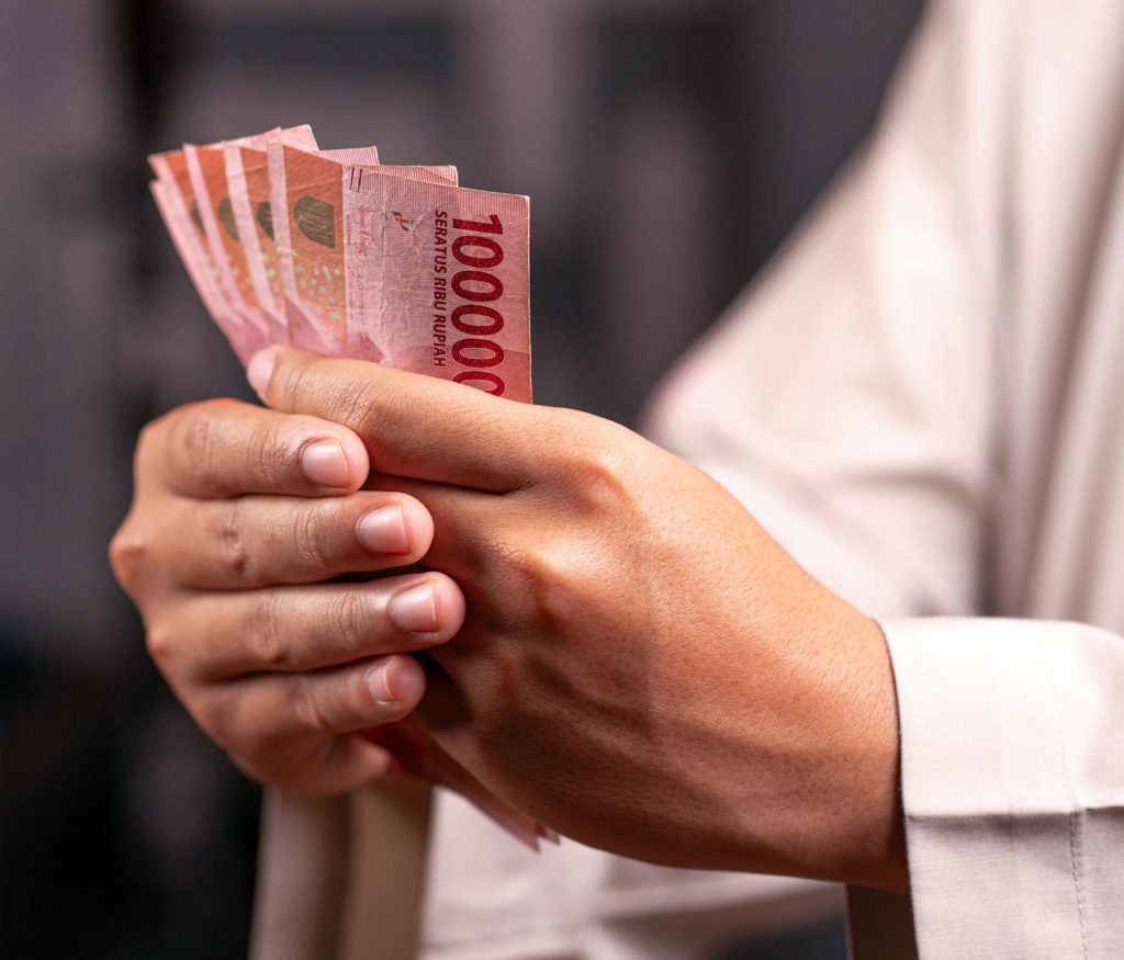 Close-up of hands holding Indonesian Rupiah 100,000 bills, highlighting financial and economic concepts.