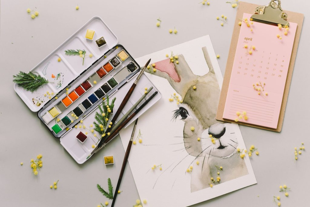 Creative Easter flat lay featuring watercolor art of bunny and painting supplies for spring inspiration.