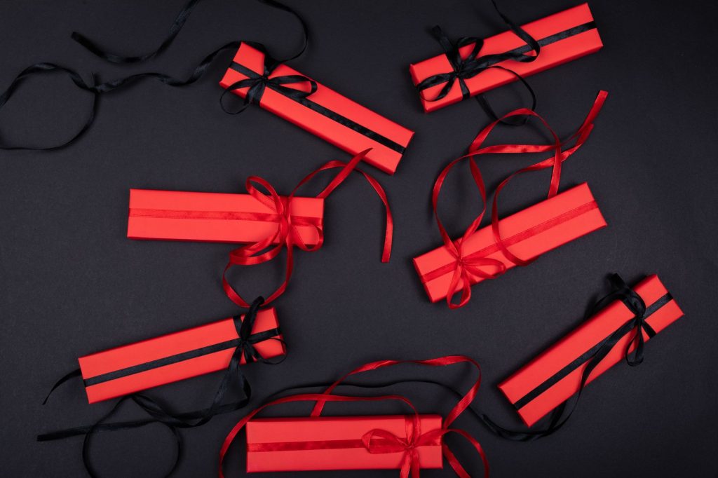 Top view of red and black wrapped gift boxes with ribbons on a black surface, ideal for festive occasions.
