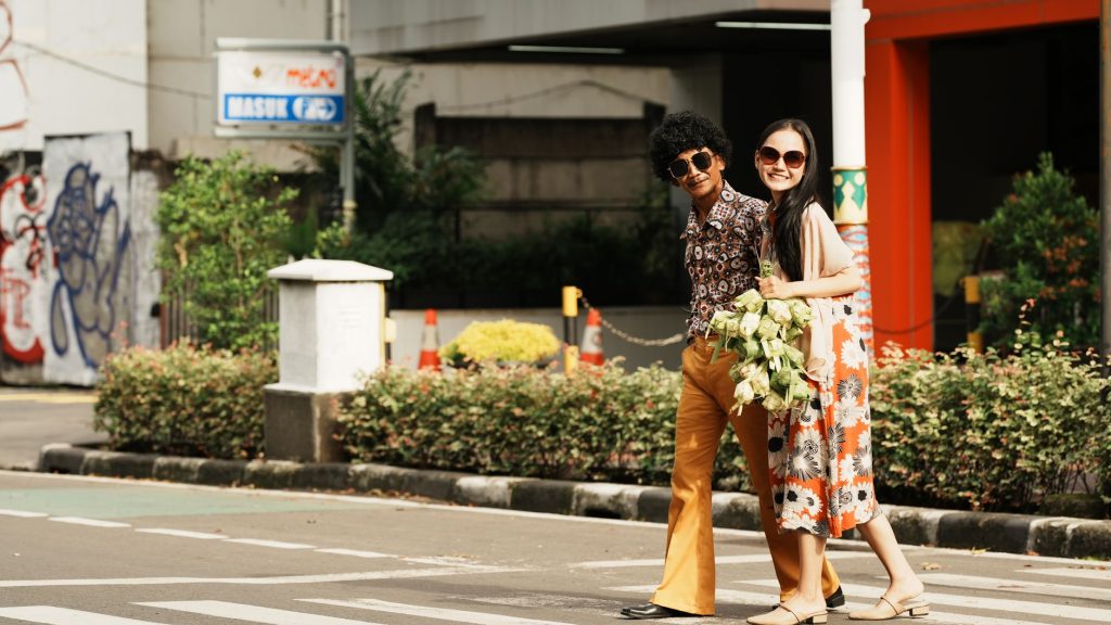 A stylish couple in retro fashion crossing the street in Jakarta, Indonesia.